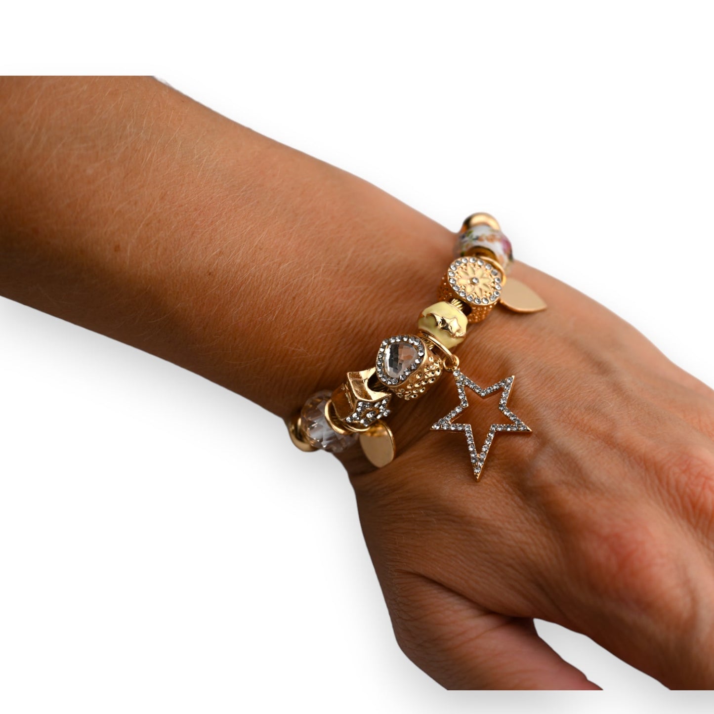 Goldenes Armband mit Anhängern und Strass-Stern auf brauner Haut, Detailaufnahme von Schmuck am Handgelenk