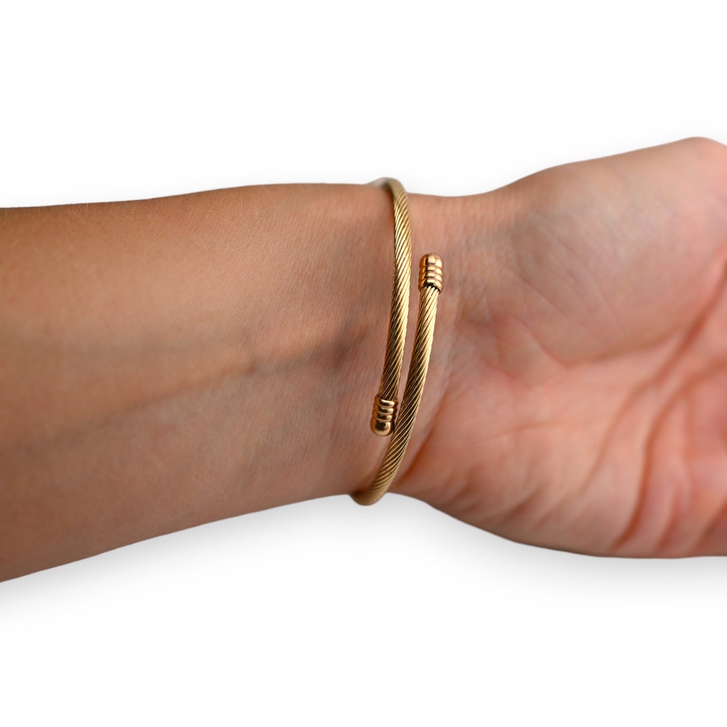 Goldenes Kabelarmband aus geflochtenem Metall mit spiralförmigem Design, am Handgelenk getragen