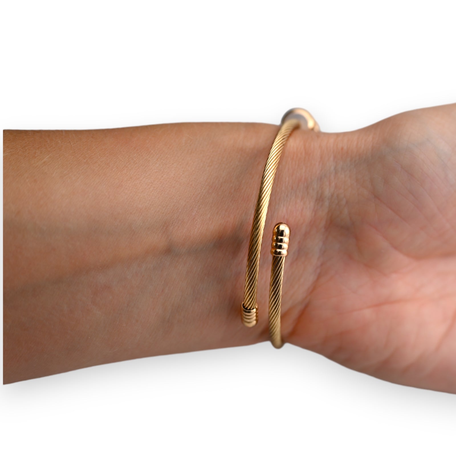 Goldenes Kabelarmband am Handgelenk, elegant gedreht mit offenen Enden und dekorativen Elementen