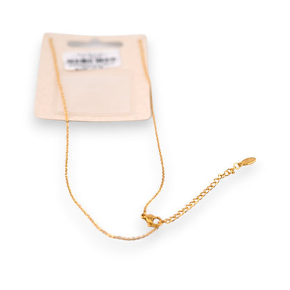 Feines goldenes Stahlhalsband mit Anhänger auf cremefarbener Verpackung, elegantes Schmuckstück für Damen