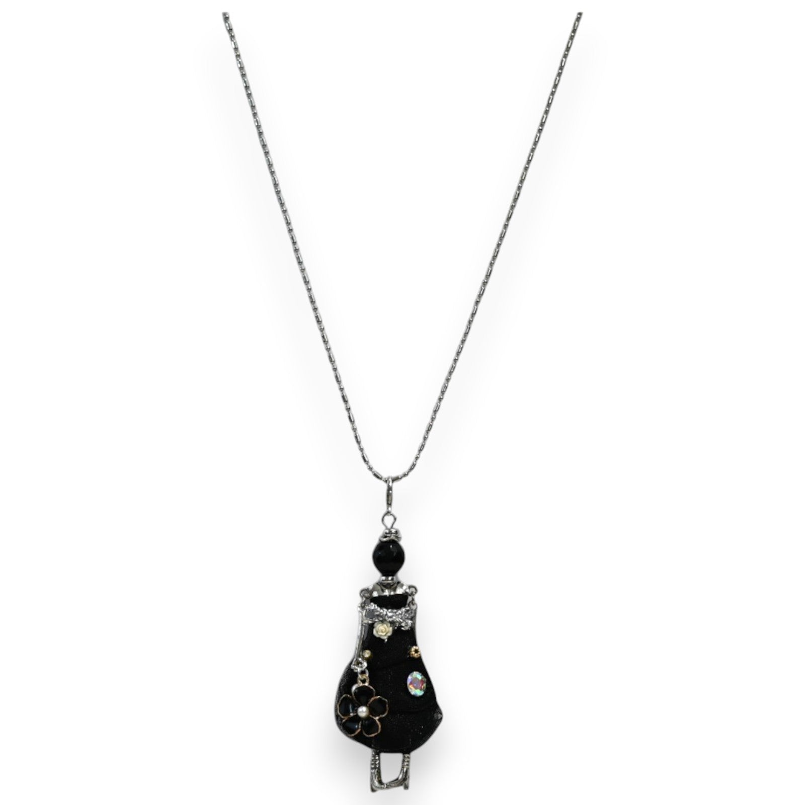 Halskette mit Anhänger: Kleine schwarze Gelenkpuppe im Kleid, verziert mit Blume und Glitzersteinen, an silberner Kette