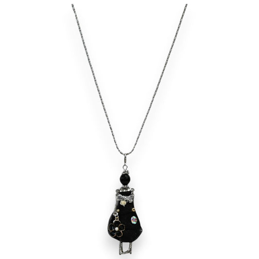 Halskette mit Anhänger: Kleine schwarze Gelenkpuppe im Kleid, verziert mit Blume und Glitzersteinen, an silberner Kette