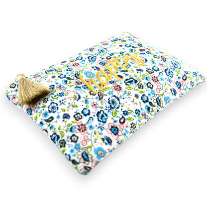 Blumige Tasche mit Liberty-Muster in Blau, Grün und Rosa, goldener 'Happy'-Schriftzug und Quaste, weißer Hintergrund