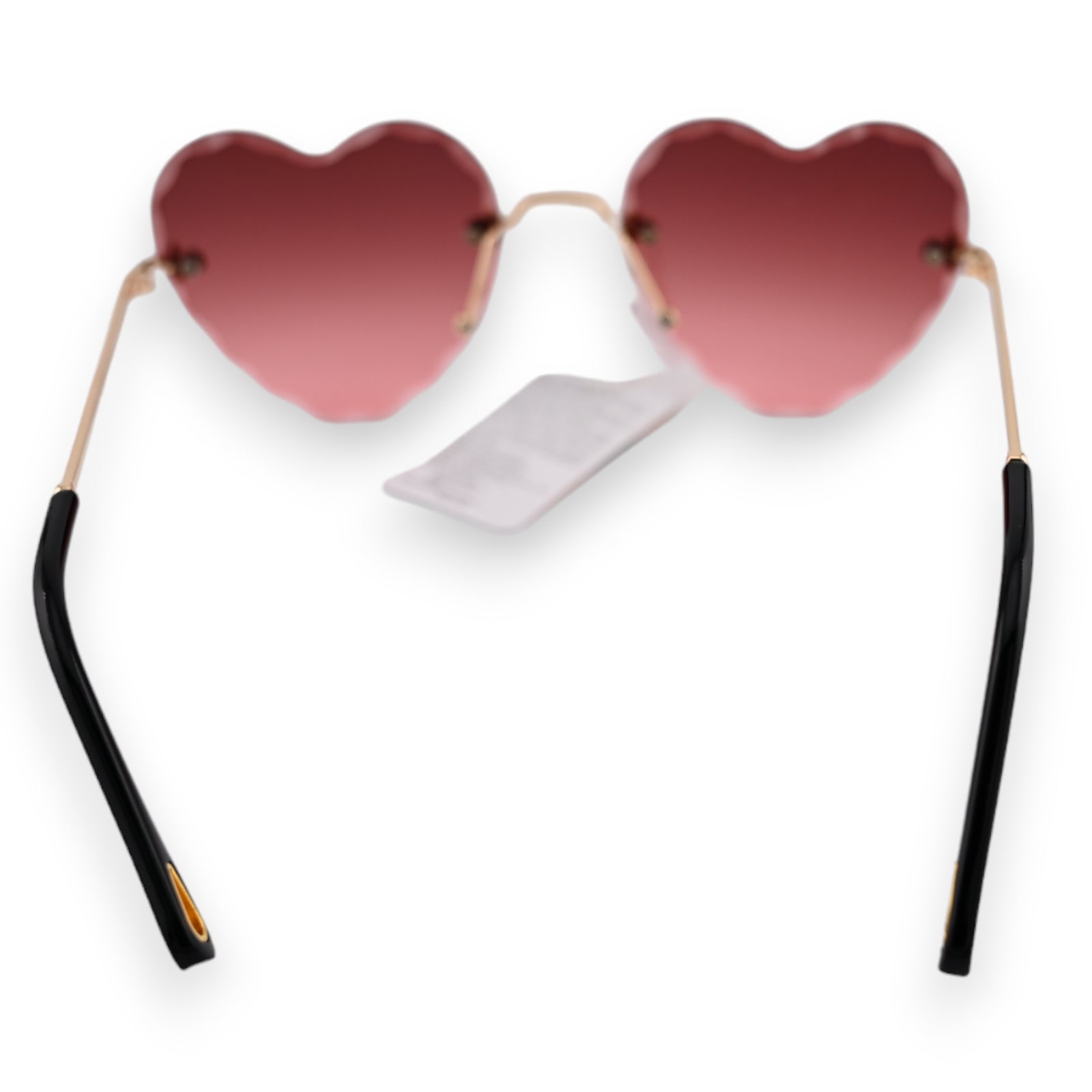 Herzförmige Sonnenbrille mit rosa-braunem Farbverlauf, goldenen Bügeln und schwarzen Enden. Weißer Hintergrund.