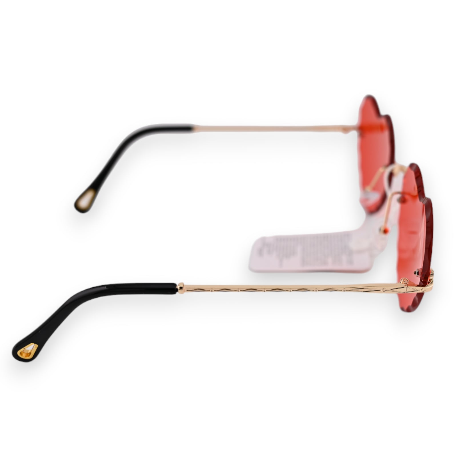 Herzförmige Sonnenbrille mit roten Gläsern, goldenen Bügeln und schwarzen Enden. Hippie-Stil, seitliche Ansicht.