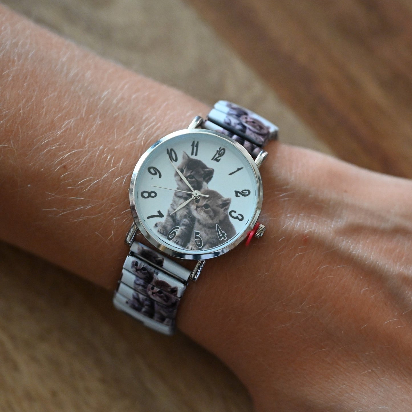 Armbanduhr mit Katzenmotiv auf Zifferblatt und Armband, getragen am Handgelenk, zeigt 2:37 Uhr