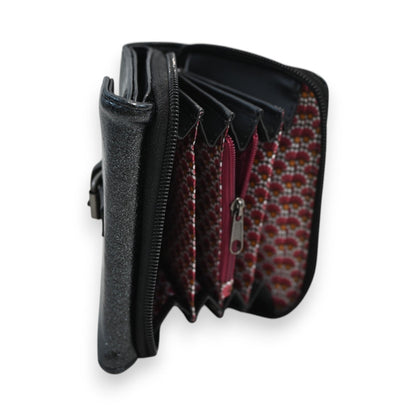 Kompakte schwarze Brieftasche mit Reißverschluss, mehreren Fächern und rot gemustertem Innenfutter, geöffnet von der Seite