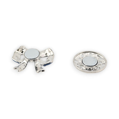 Magnetische Brosche mit silberfarbigem Schmetterling und rundem Magnet, daneben dekorative Magnetplatte mit Blumenmuster