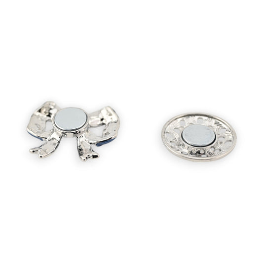 Magnetische Brosche mit silberfarbigem Schmetterling und rundem Magnet, daneben dekorative Magnetplatte mit Blumenmuster