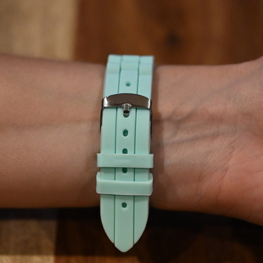 Nahaufnahme einer hellgrünen Silikonarmbanduhr am Handgelenk, mit silberner Schnalle und strukturiertem Band