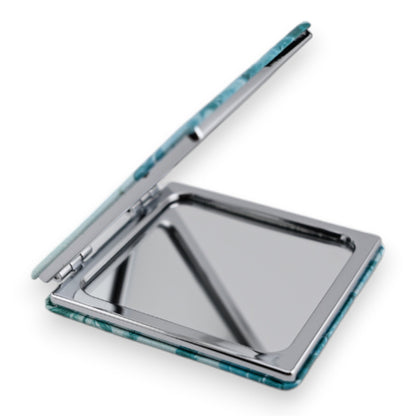 Kompakter Reisespiegel mit türkisfarbenem Muster, aufgeklappt mit Spiegelfläche sichtbar, quadratische Form