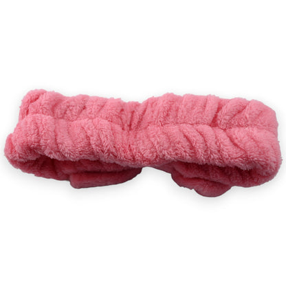 Flauschige pinkfarbene Stirnbinde aus weichem Plüsch für Make-up und Gesichtspflege, isoliert auf weißem Hintergrund
