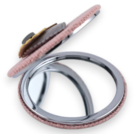 Rosafarbener Taschenspiegel mit 3D-Herzen-Blume, grauem Bezug und silbernem Rahmen auf weißem Hintergrund