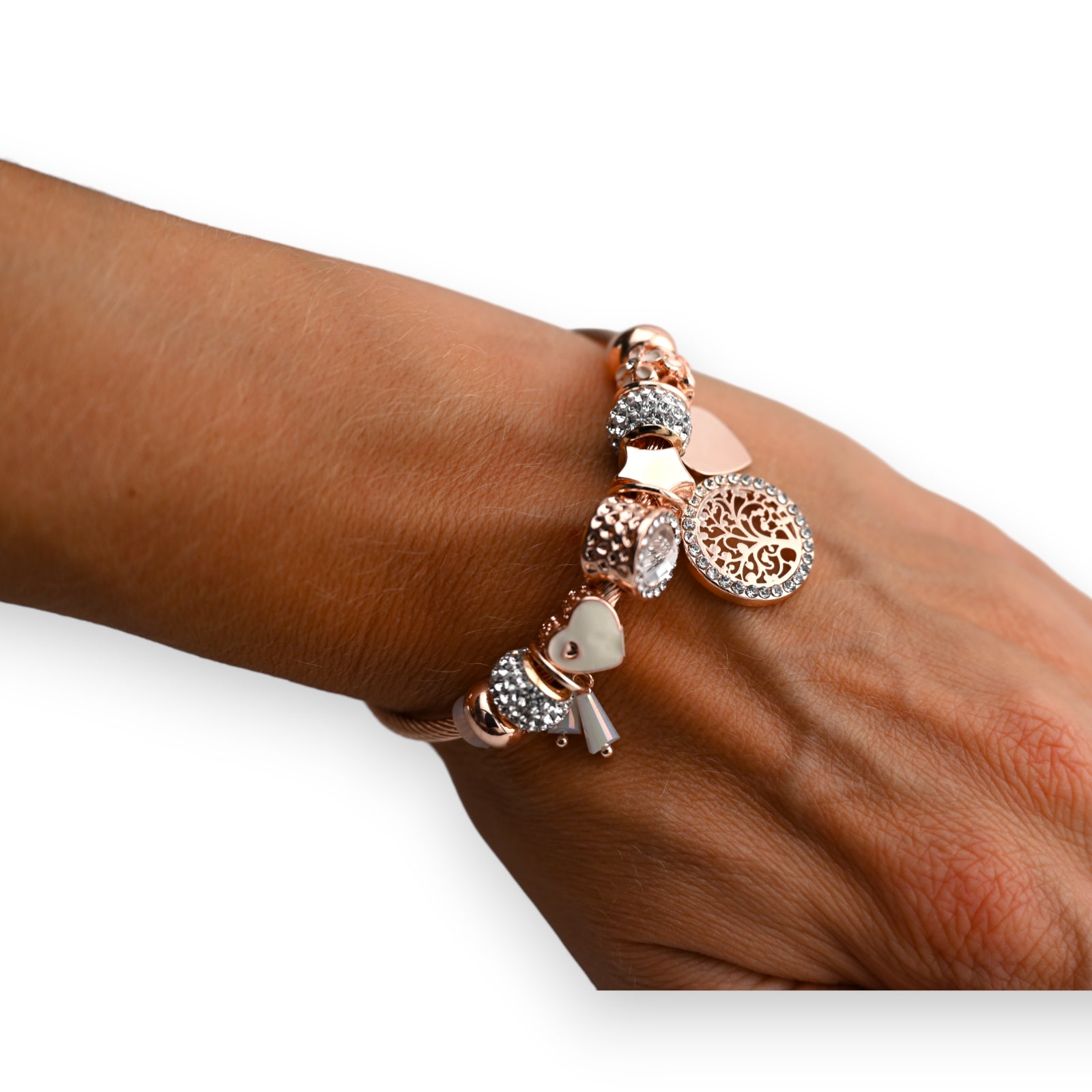 Rosegoldenes Charm-Armband mit Baum des Lebens Anhänger, Herzen und Kristallen auf dunklem Handgelenk
