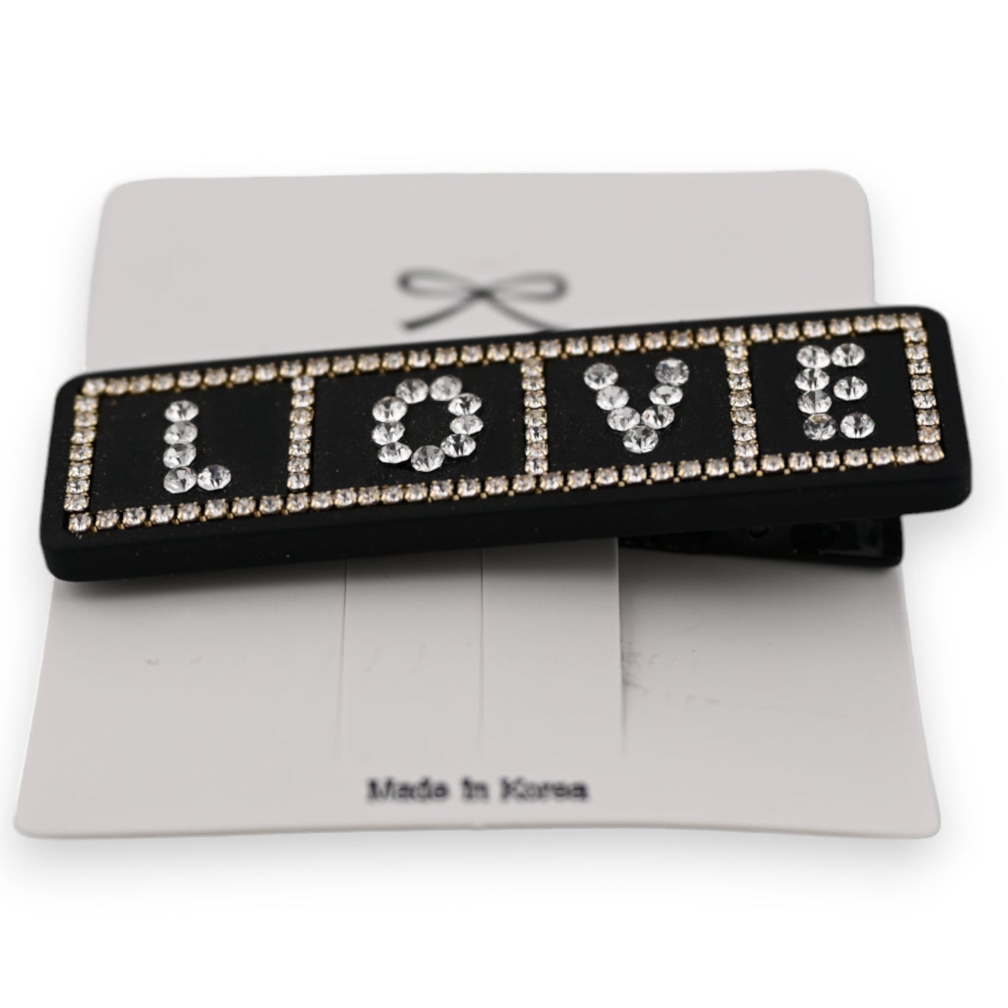 Schwarze Haarspange mit LOVE-Schriftzug aus Strasssteinen, auf weißer Karte mit Made in Korea Aufdruck
