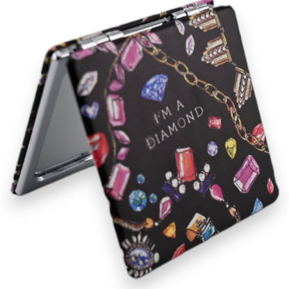 Taschenspiegel mit schwarzem Hintergrund und bunten Schmuckmotiven wie Diamanten, Edelsteinen und Ketten. Aufschrift 'I'm ...