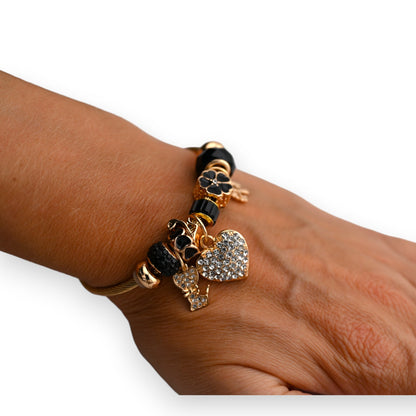 Elegantes Armband mit schwarzen Perlen und goldenen Anhängern, darunter ein Herz mit Strasssteinen besetzt