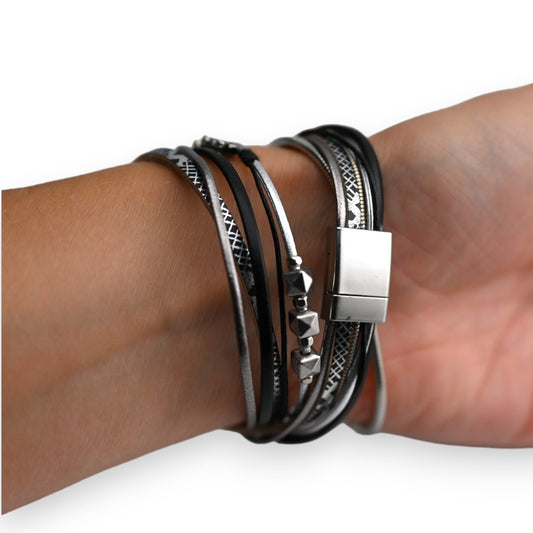 Mehrreihiges schwarzes Lederarmband mit silbernen Details und Magnetverschluss am Handgelenk einer Person