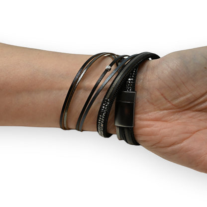 Schwarzes Lederarmband mehrfach gewickelt mit Charmes und grauen Strasssteinen an einem Handgelenk