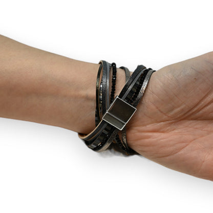 Mehrschichtiges schwarzes Lederarmband mit glitzernden Perlen und Metallverschluss am Handgelenk getragen