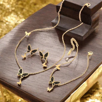 Goldenes Schmuckset mit schwarzen Schmetterlingen und Sternen: Halskette und Ohrringe auf Holzunterlage