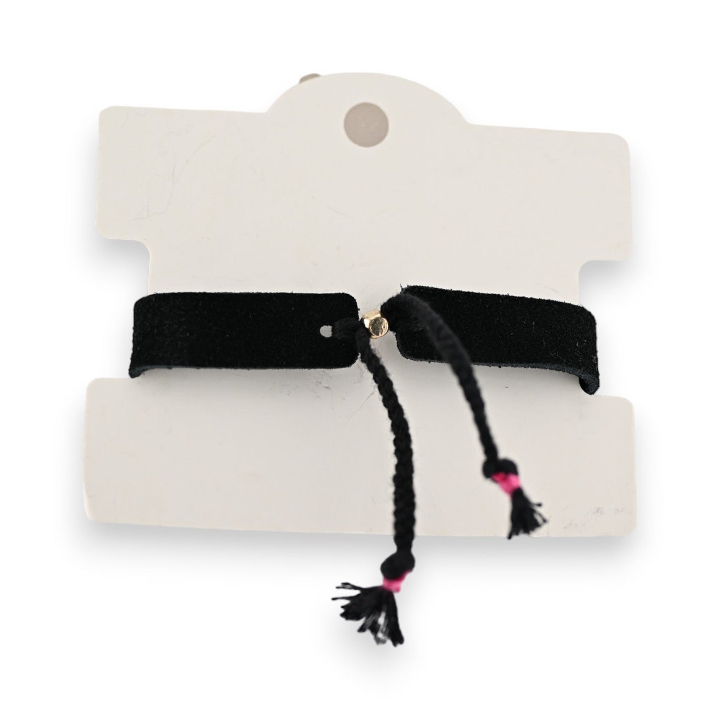 Schwarzes Stoffarmband auf weißem Karton, mit zwei Quasten und pinken Akzenten, modisches Accessoire