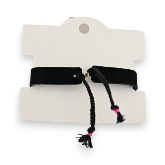Schwarzes Stoffarmband auf weißem Karton, mit zwei Quasten und pinken Akzenten, modisches Accessoire