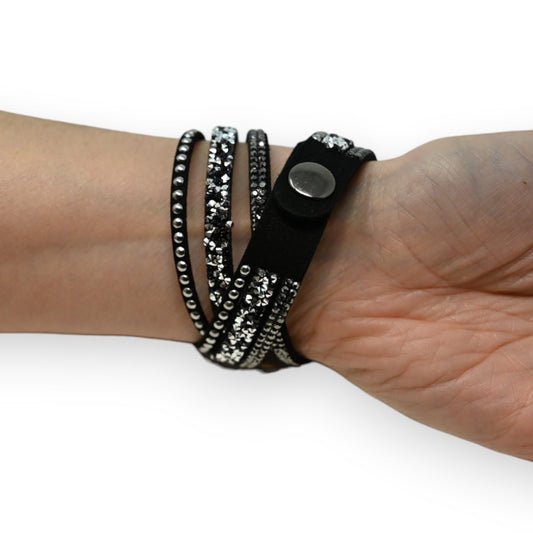 Schwarzes Doppelarmband mit Strass-Steinen und Nieten, mehrfach um das Handgelenk gewickelt, auf hellem Hintergrund