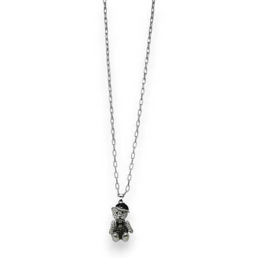 Lange silberne Kette mit glitzerndem Teddybär-Anhänger, der eine kleine Kappe trägt. Modisches Schmuckstück.