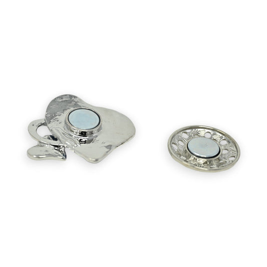 Magnetische Brosche mit silbernem Herz-Design und hellblauem Stein, daneben runde Zierplatte mit Magnetverschluss