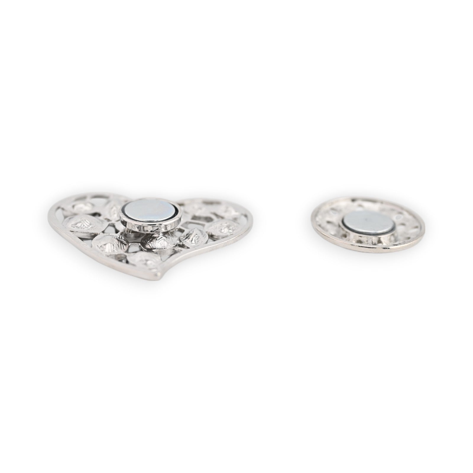 Silberne magnetische Brosche in Herzform mit filigran verziertem Design und rundem Magnet, daneben ein kleinerer runder Ma...
