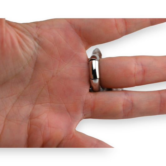 Nahaufnahme einer Hand mit glänzendem silbernen Ring am Finger, runde Form, glatte Oberfläche, elegant und schlicht