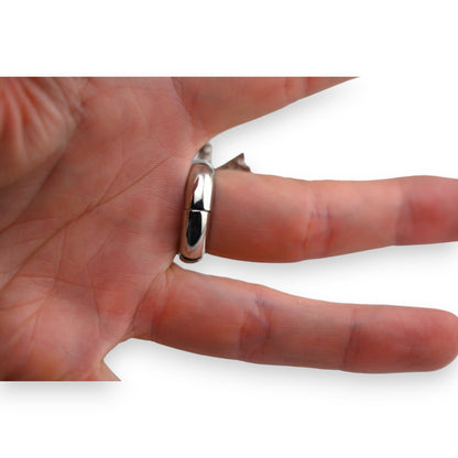Glänzender Silberring am Finger, schlichtes Design mit glattem, gewölbtem Profil, auf weißem Hintergrund