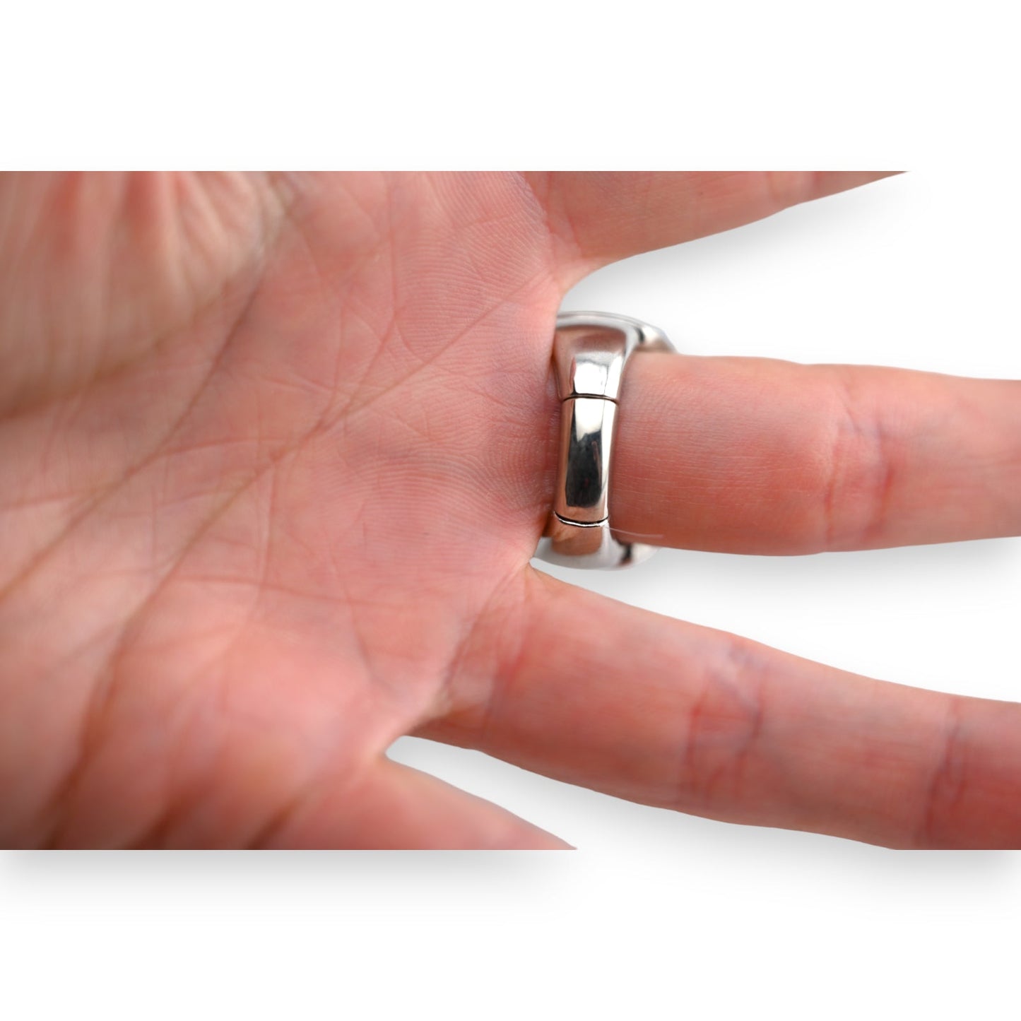 Nahaufnahme eines glänzenden Silberrings am Finger, der die Struktur und Details des Rings zeigt