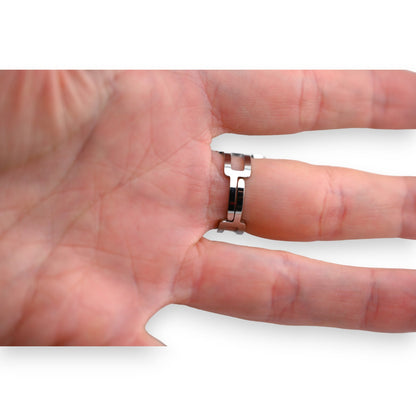 Silberner Stahlring mit ovaler geometrischer Form an einem Finger, Nahaufnahme der Hand und des Rings