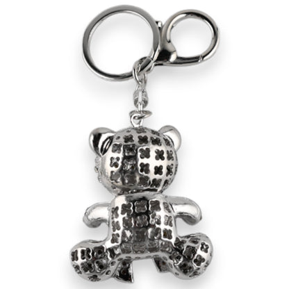 Silberner Schlüsselanhänger in Form eines sitzenden Teddybären mit geometrischem Muster und Ohren, an einem Metallring bef...