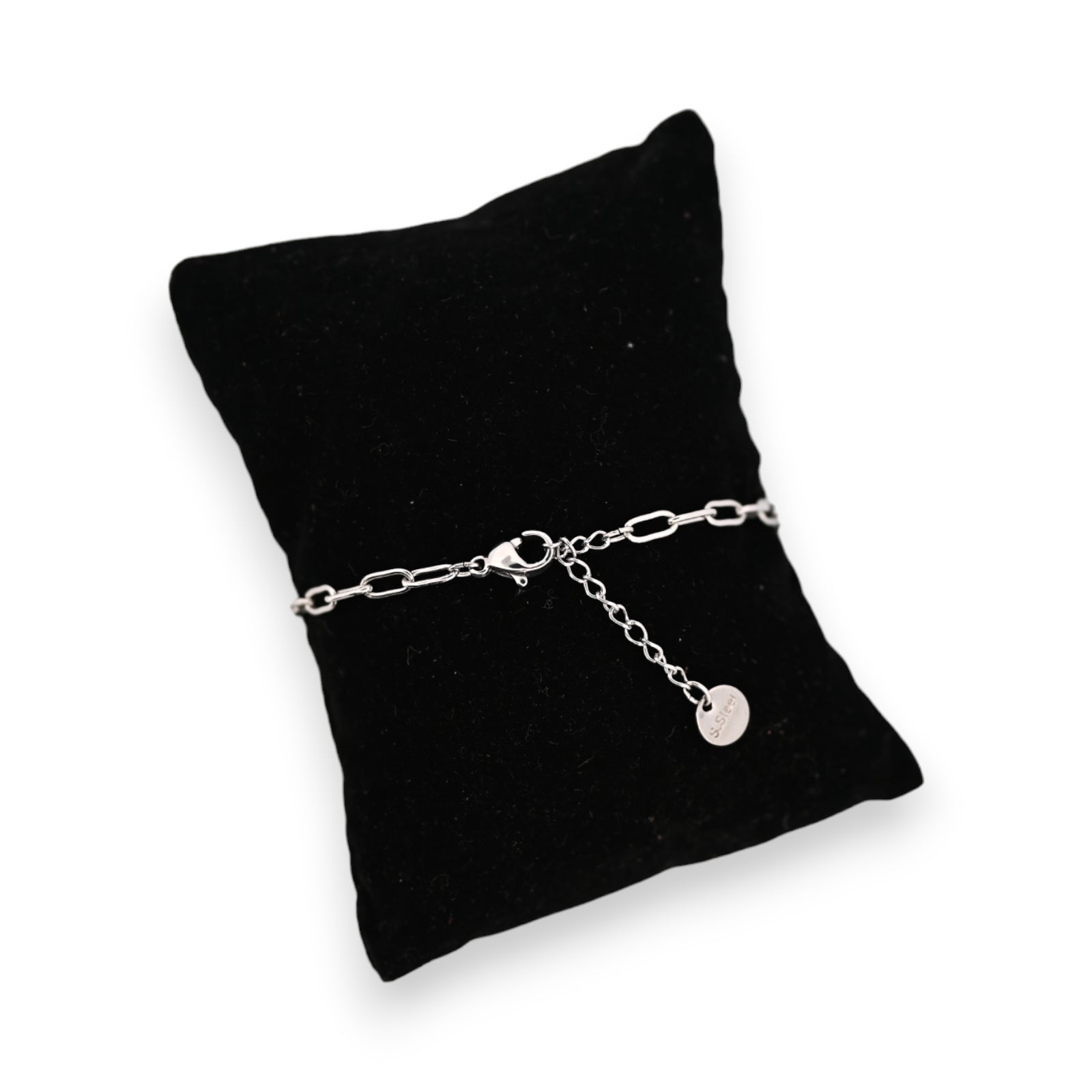 Silbernes Stahlarmband auf schwarzem Samtkissen mit kleinem Anhänger, elegantes Schmuckstück für Damen