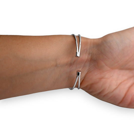 Minimalistisches silbernes Armband mit geometrischem Design, zwei dünne Metallstränge mit Endkappen, am Handgelenk getragen
