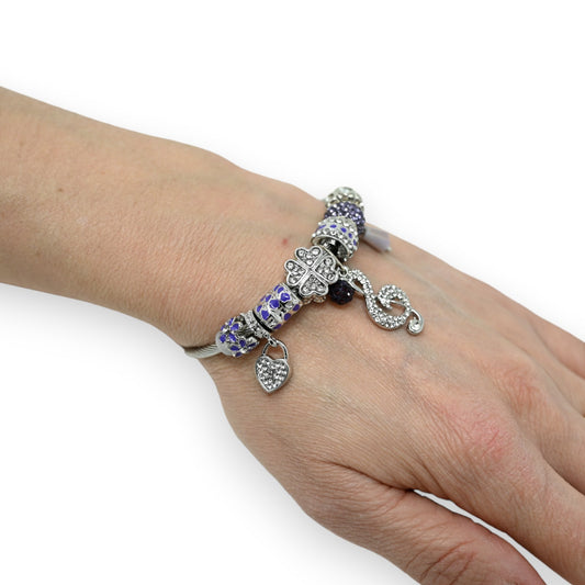 Silbernes Charm-Armband mit lila Perlen, Herz- und Kleeblatt-Anhängern sowie Notenschlüssel-Charm auf Handgelenk