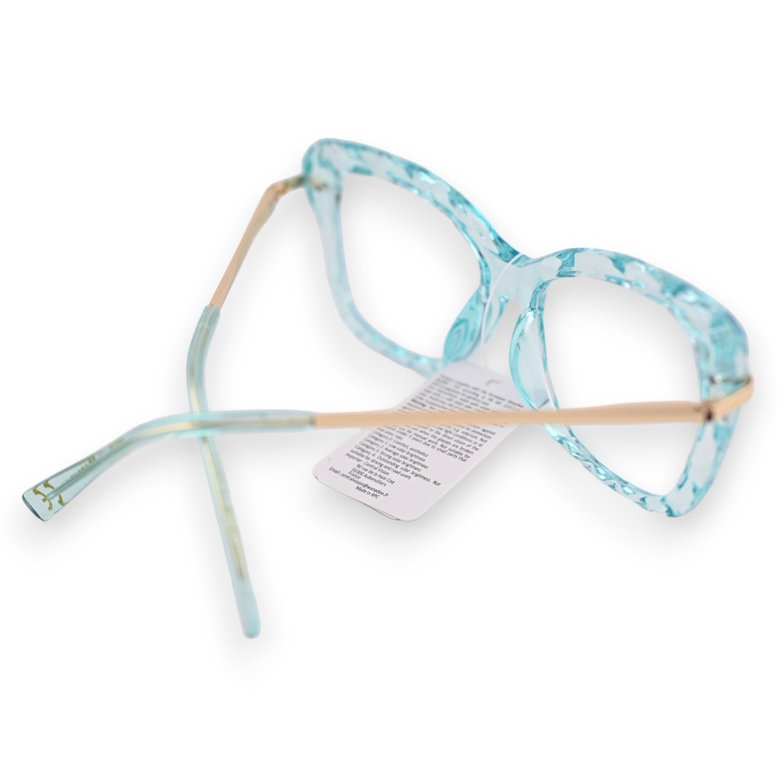 Transparente türkisfarbene Brille mit goldenen Bügeln und Produktetikett, auf weißem Hintergrund