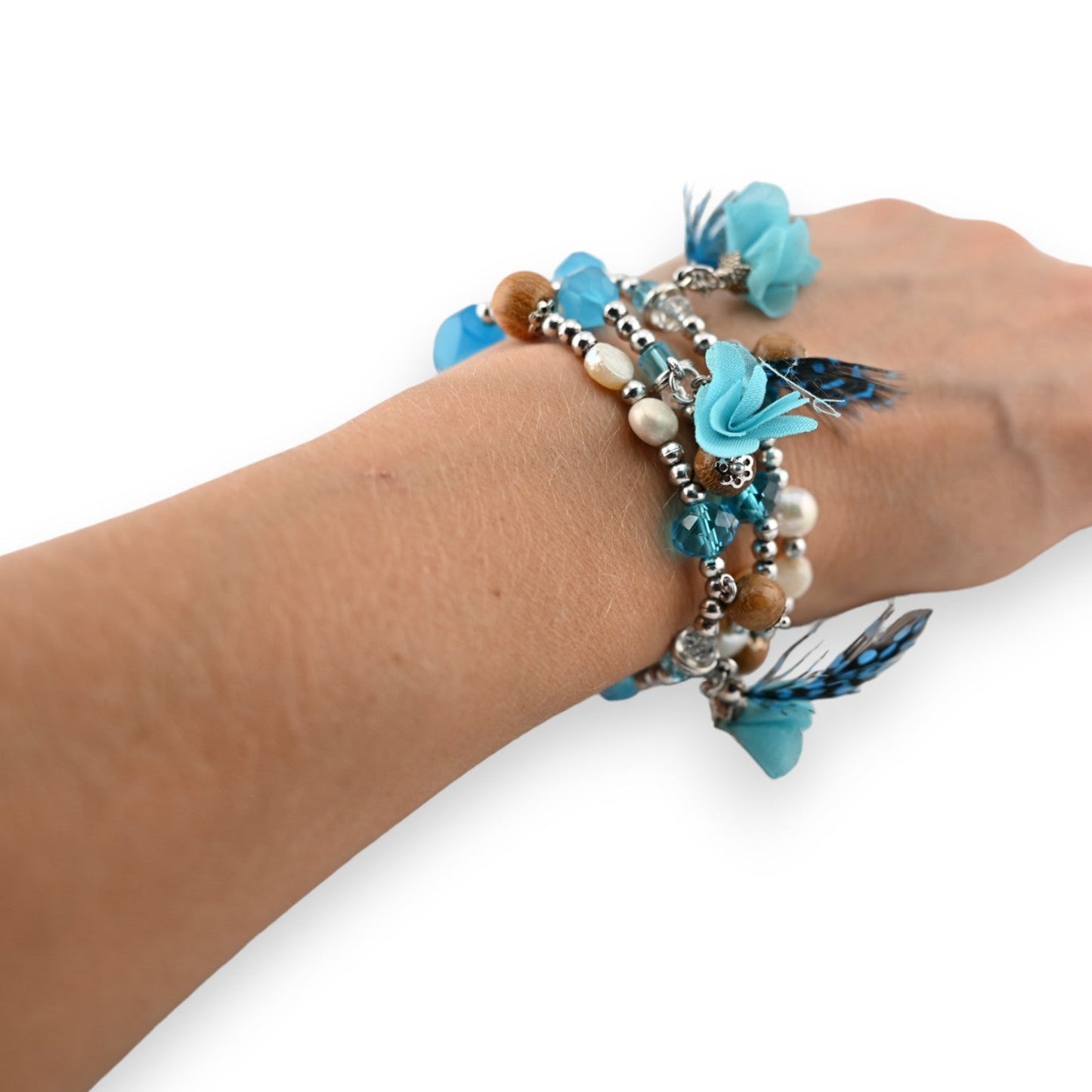 Elastische Modeschmuckarmbänder mit türkisfarbenen Blüten, Federn, Perlen und Kristallen am Handgelenk einer Frau