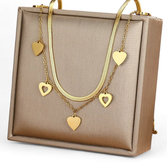 Vergoldete Doppelkette mit Herzanhängern auf beigem Schmuckkästchen, elegantes Accessoire für Damen