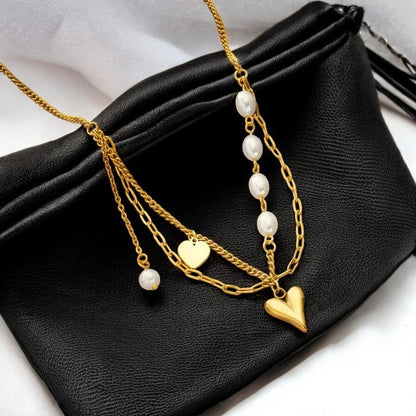 Vergoldete Stahlkette mit Herzanhängern und Perlen auf schwarzer Ledertasche, elegantes Schmuckstück