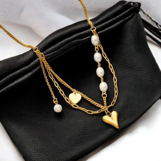 Vergoldete Stahlkette mit Herzanhängern und Perlen auf schwarzer Ledertasche, elegantes Schmuckstück