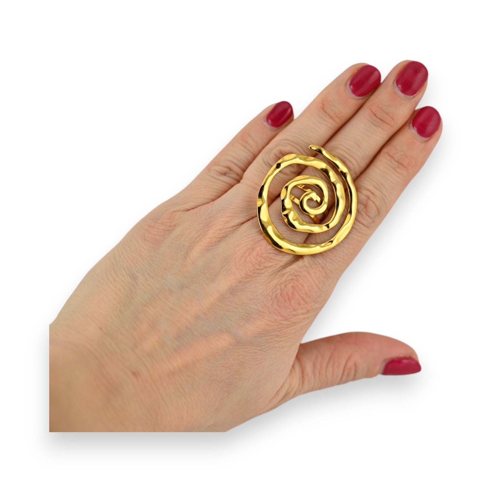 Verstellbarer goldener Spiralring aus Edelstahl an einer Hand mit rot lackierten Nägeln auf weißem Hintergrund