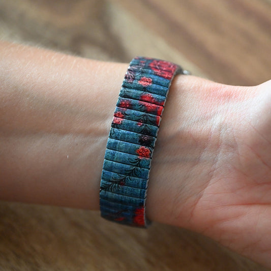 Vintage-Armband mit blau-rotem Blumenmuster auf Handgelenk, elastisches Design mit feinen Metallgliedern