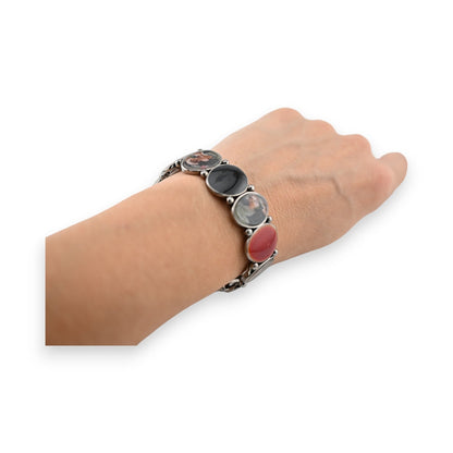 Elastisches Vintage-Armband mit bunten runden Blumenanhängern auf silbernem Metall, am Handgelenk getragen