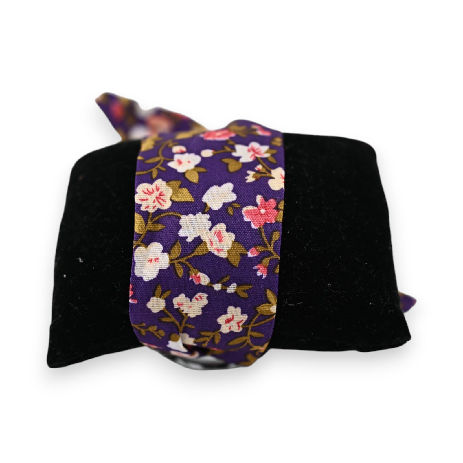 Elegante Armbanduhr mit violettem Blumenmuster-Stoffarmband auf schwarzem Samtkissen, florales Design