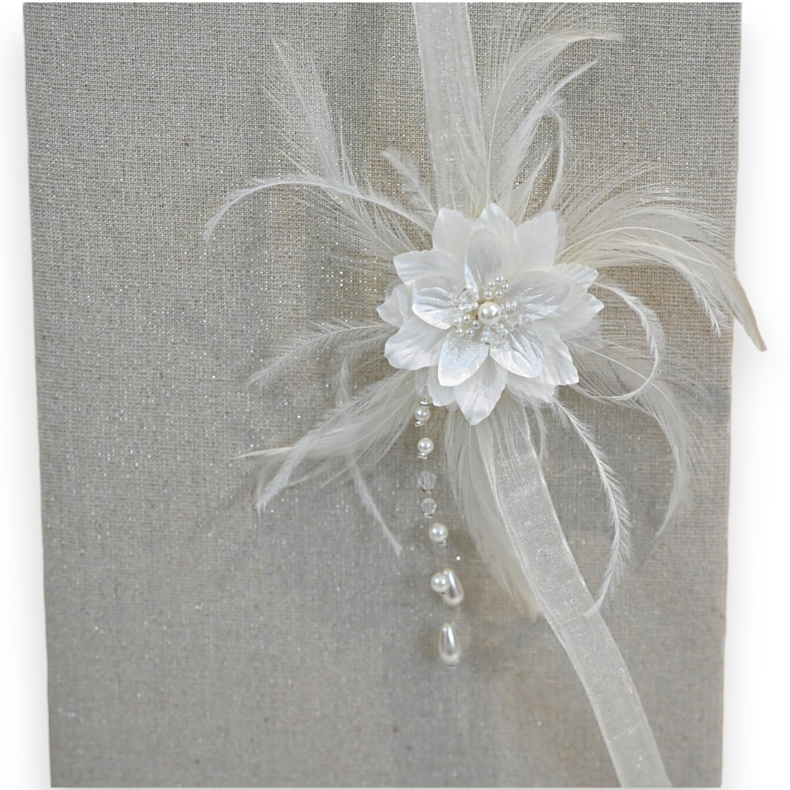 Eleganter weißer Haarschmuck mit Blüte, Federn und Perlen auf glitzerndem Hintergrund, perfekt für Bräute